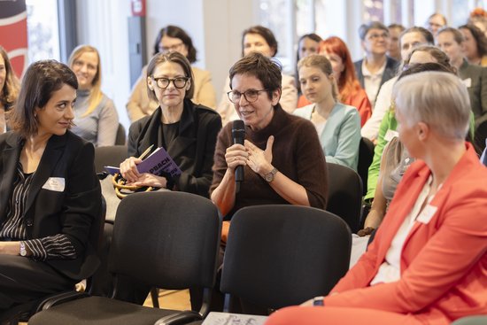 Accessories,  Adult,  Crowd,  Electrical Device,  Female,  Glasses,  Microphone,  Person,  Woman,  Wristwatch